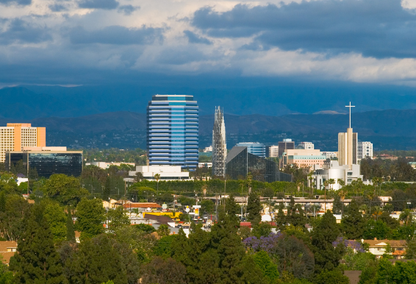City skyline with trees and mountains in the background, showcasing the harmonious blend of urban and natural elements in Garden Grove California.